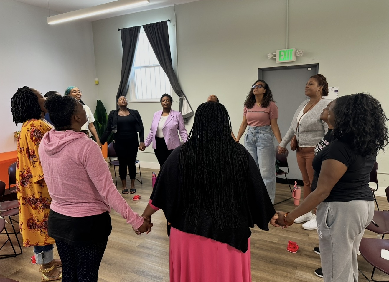 Women gathered in a circle holding hands at a She Stories event